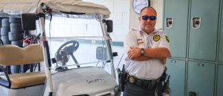 PHSC Officer standing next to golf cart. 
